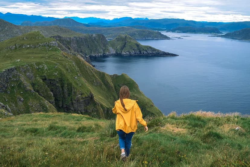 Ein Mädchen geht durch ein norwegisches Bergland mit einem atemberaubenden Blick auf das Meer und die Berge, eine unvergessliche Erfahrung während des Austauschjahres.