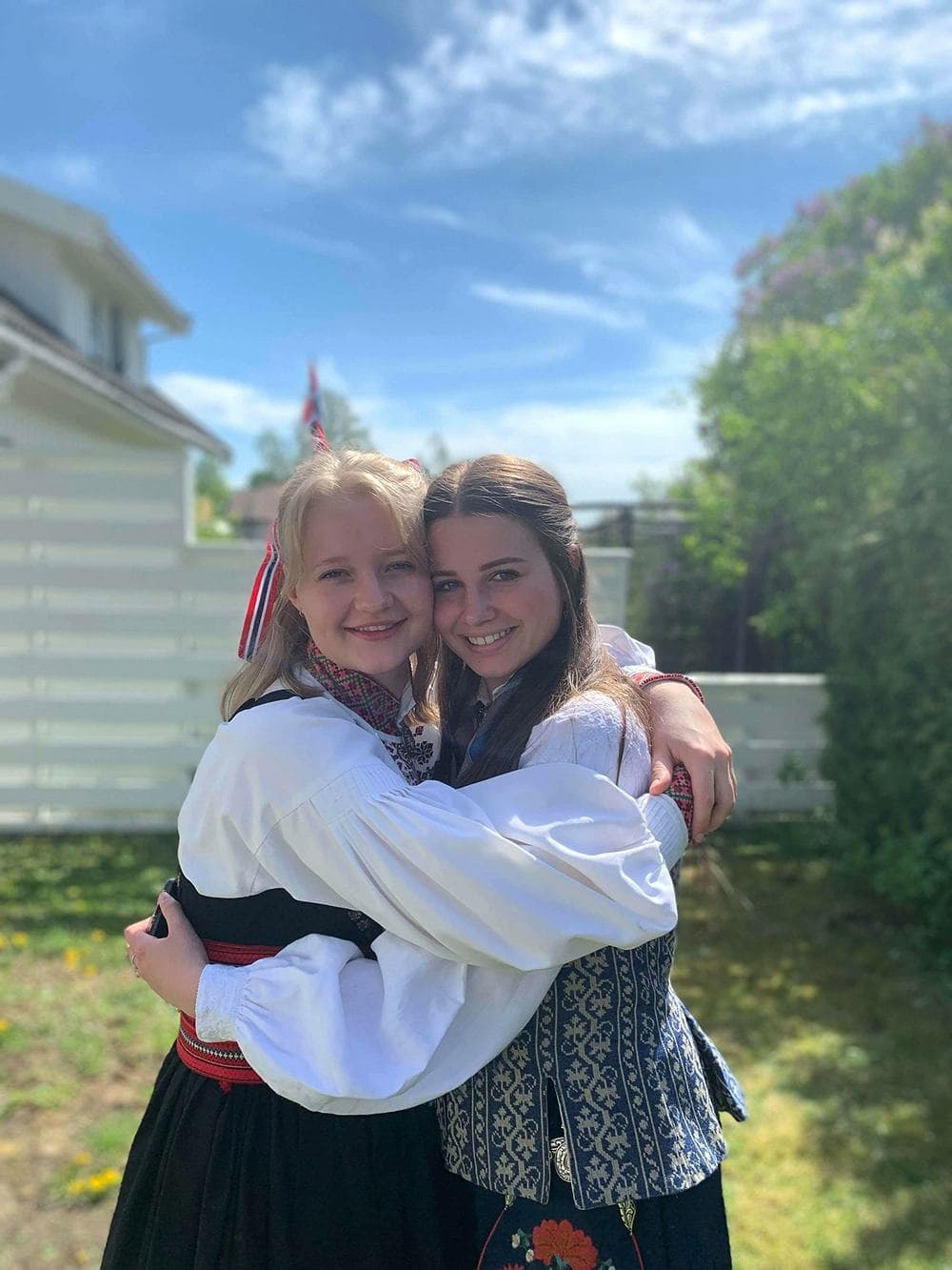 Zwei Mädchen in traditioneller norwegischer Kleidung umarmen sich, während sie eine kulturelle Austausch-Erfahrung in Norwegen während des Austauschjahres machen.